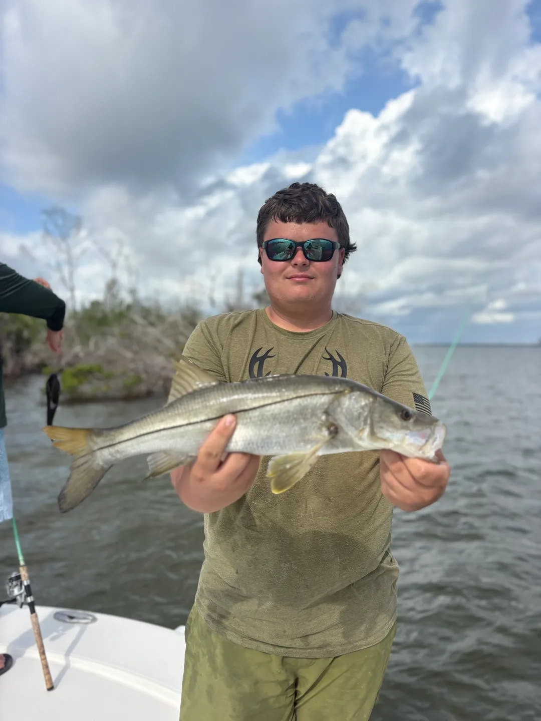 Person holding a fish by the water