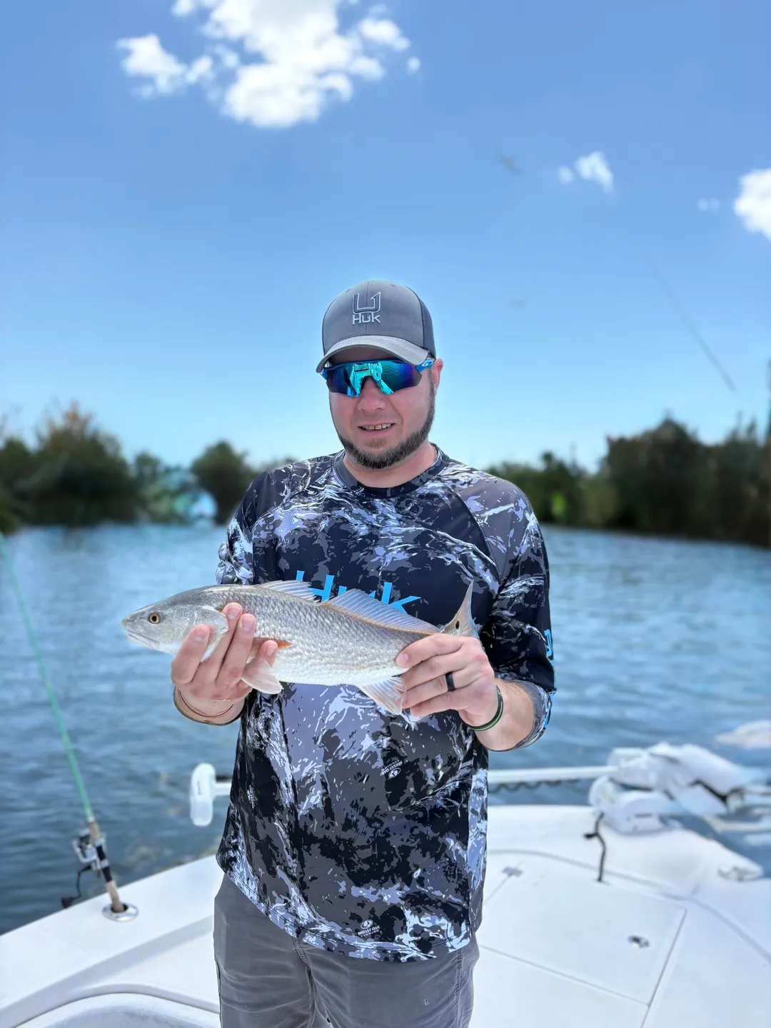 Person displaying fish under blue sky