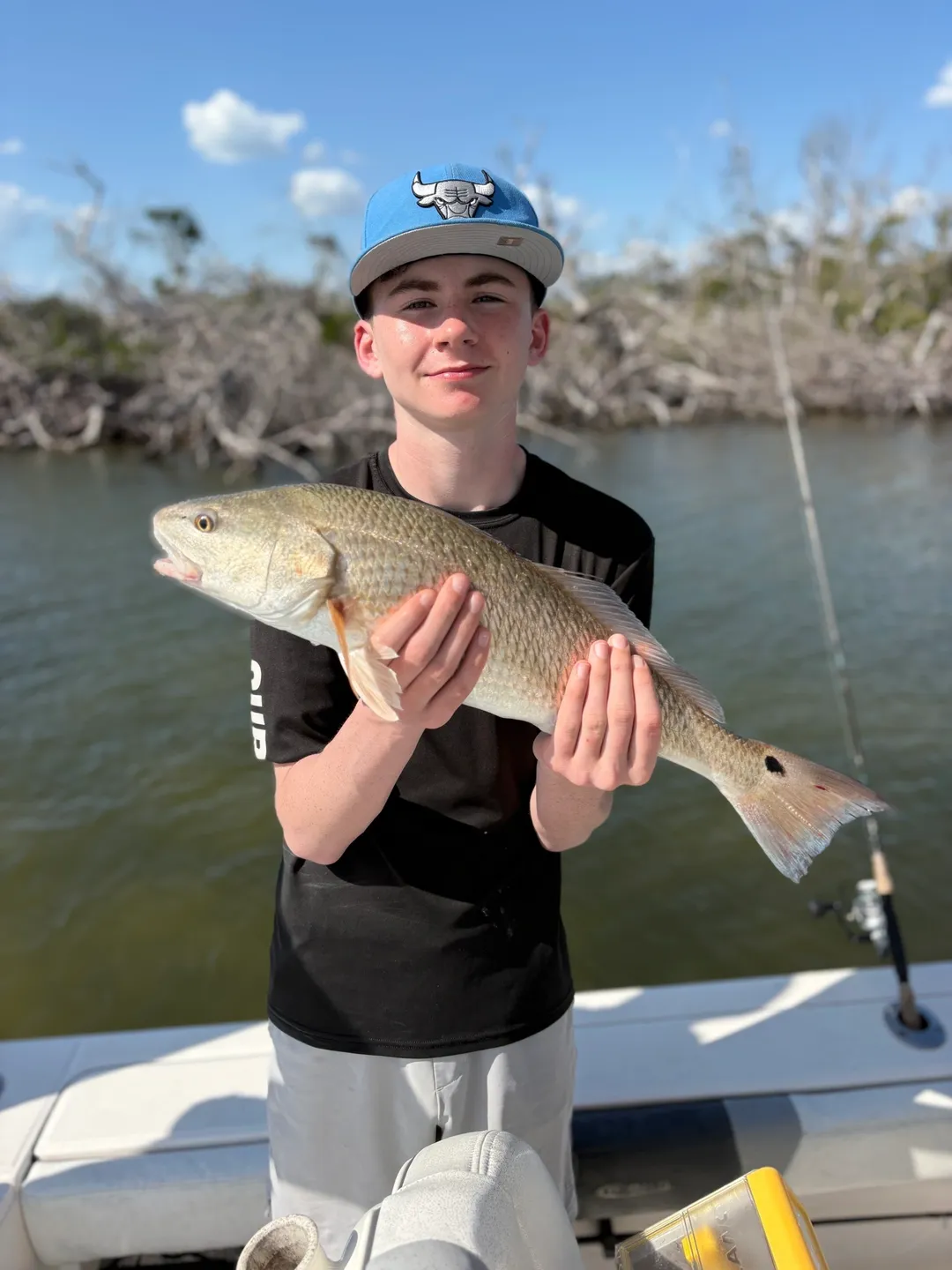 Teen holding a fish on a boat