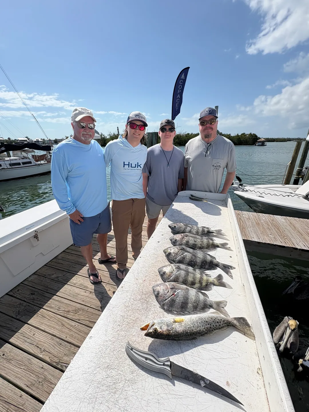 Four men posing with fish on pier